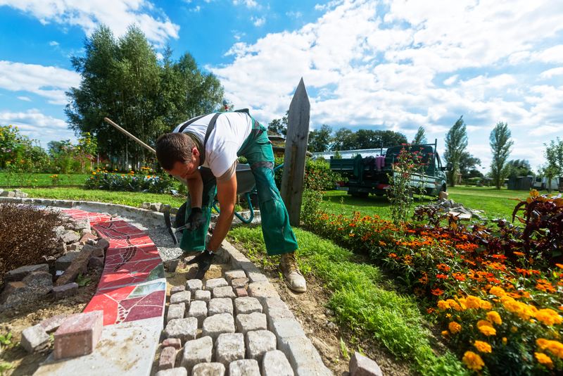 Gärtner verlegt Natursteinpflaster an einem Gartenweg